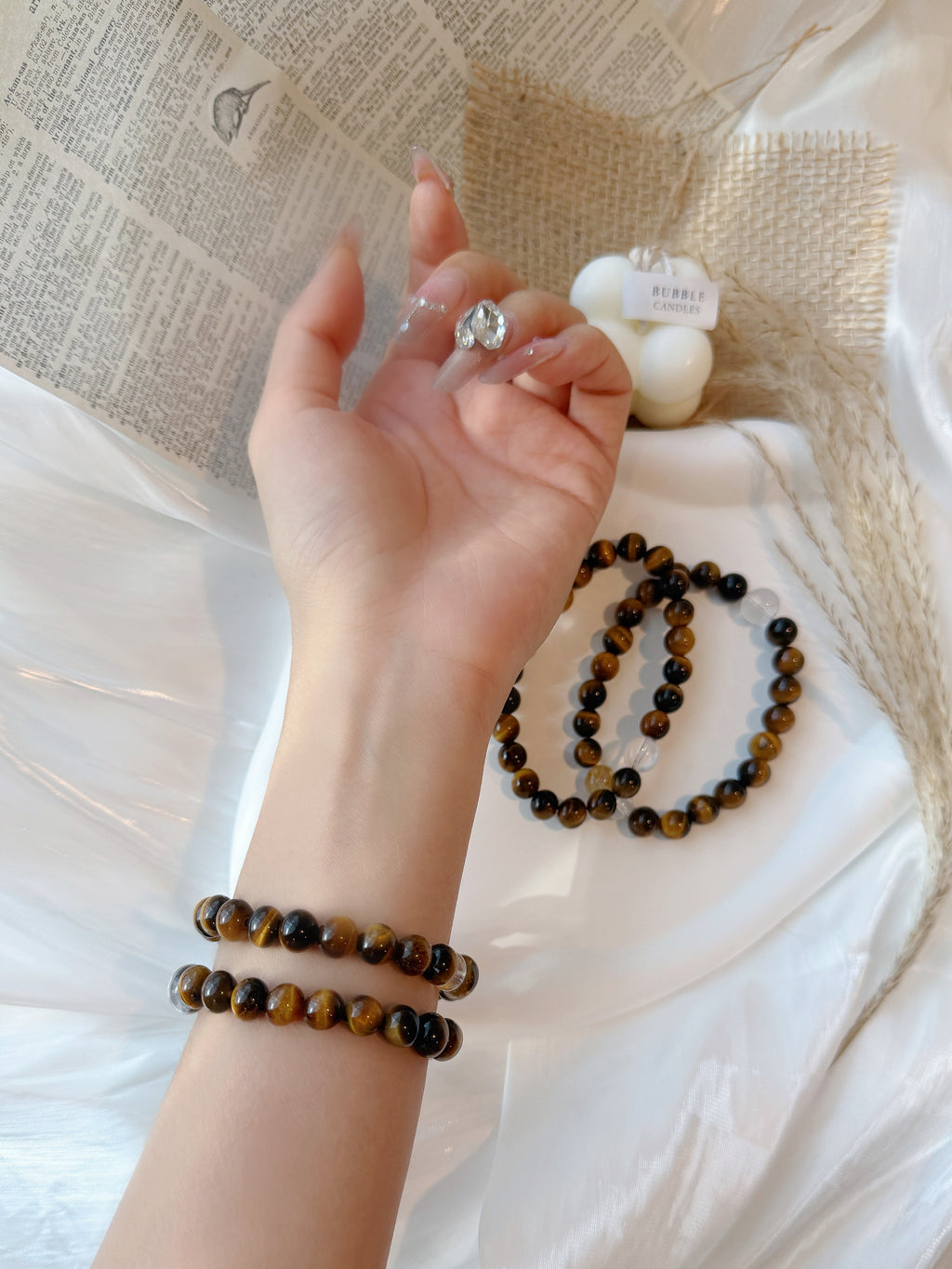 Hand wearing a ring and bracelets on a light fabric background